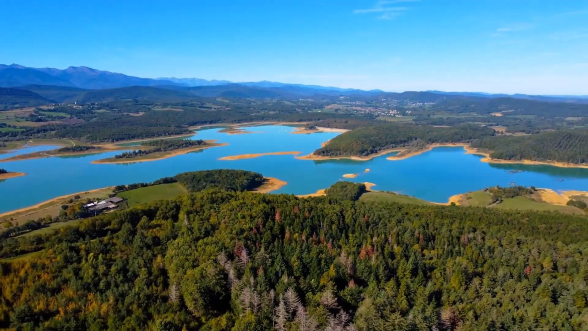 Vue aérienne du lac de Montbel, entouré de forêts et de collines.